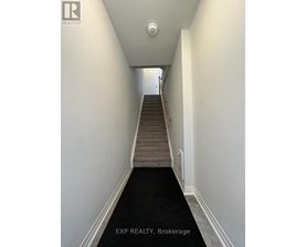 A hallway with a staircase leading to a door at the end.