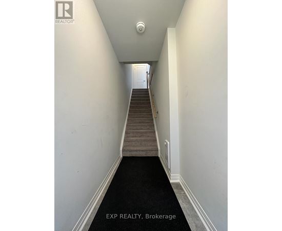 A hallway with a staircase leading to a door at the end.