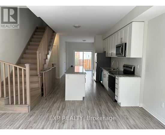 A kitchen with white cabinets and a staircase.