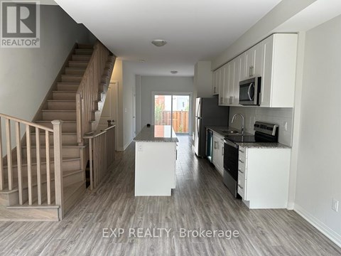 A kitchen with white cabinets and a staircase.