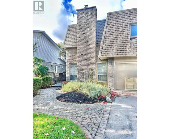 A house with a grey garage door and a stone wall.