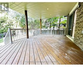 A wooden deck with a white ceiling and a brick wall.
