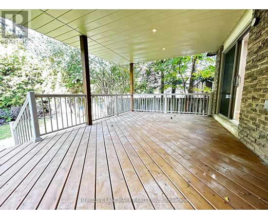 A wooden deck with a white ceiling and a brick wall.
