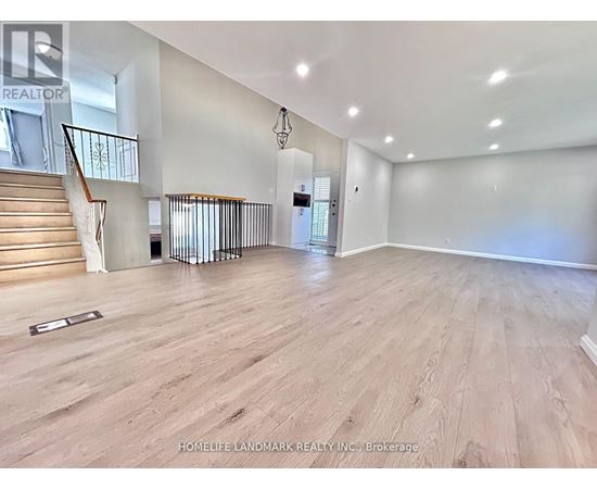 A spacious room with wooden flooring and a staircase with a metal railing.
