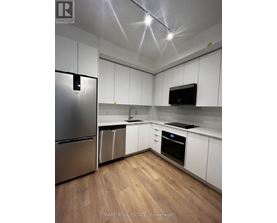 A kitchen with white cabinets and a stainless steel refrigerator.