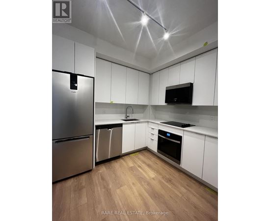 A kitchen with white cabinets and a stainless steel refrigerator.