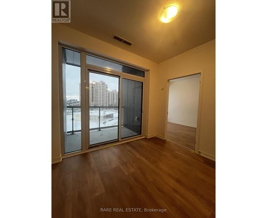A room with a sliding glass door and wooden flooring.
