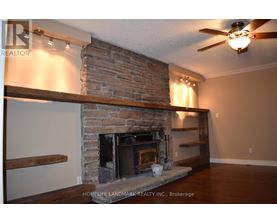 A living room with a fireplace and a ceiling fan.