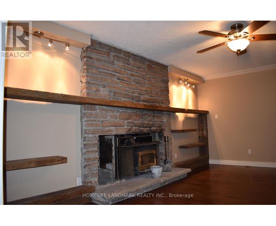 A living room with a fireplace and a ceiling fan.
