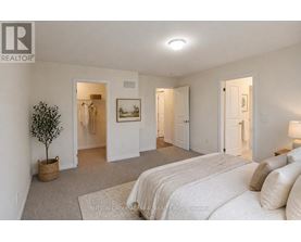 A bedroom with a large bed and a small tree in a basket.