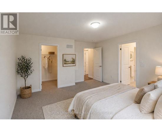 A bedroom with a large bed and a small tree in a basket.