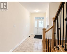 A hallway with a wooden staircase and a white door.