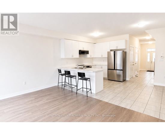 A kitchen with white cabinets and a black bar stool.