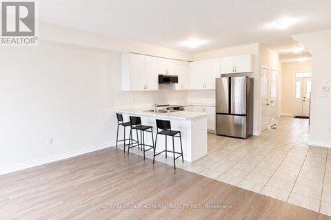 A kitchen with white cabinets and a black bar stool.