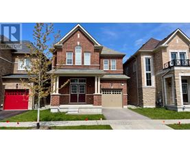 A large brick house with a red garage door is in front of a smaller house.