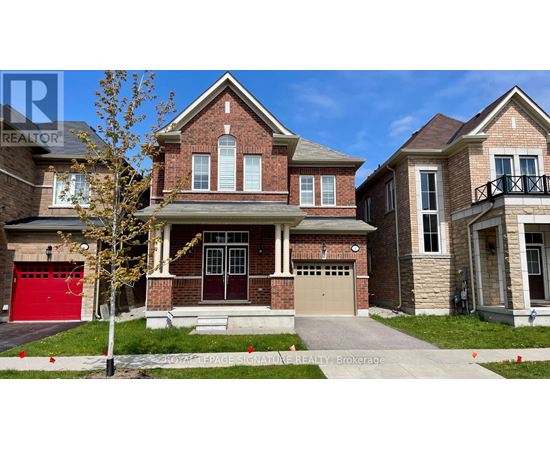 A large brick house with a red garage door is in front of a smaller house.