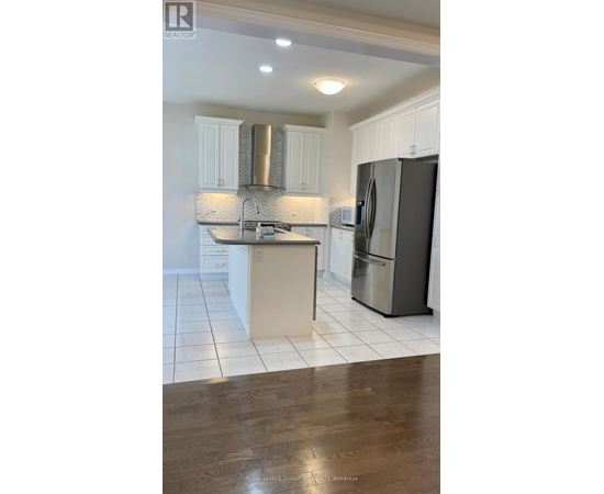 A kitchen with white cabinets and a black fridge.