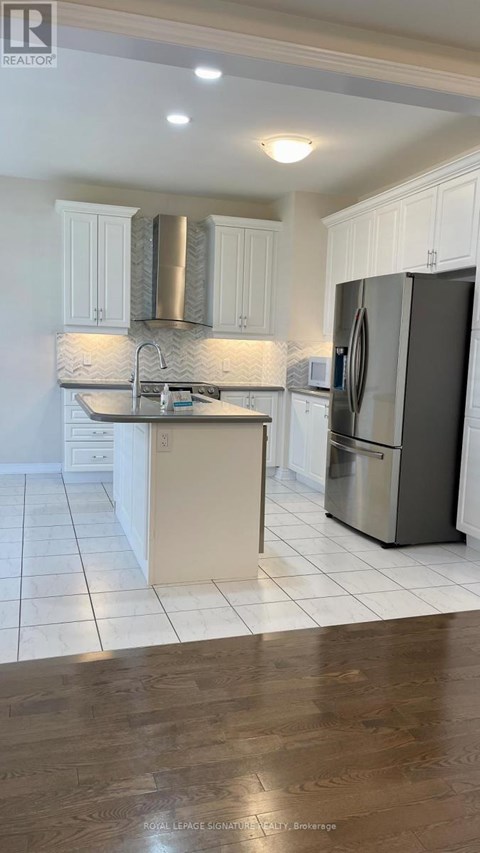 A kitchen with white cabinets and a black fridge.