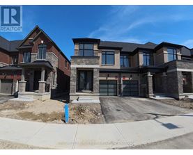 A real estate sign is displayed in front of a row of new houses.
