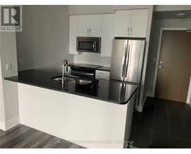 A kitchen with a black countertop and stainless steel appliances.