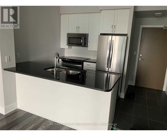 A kitchen with a black countertop and stainless steel appliances.