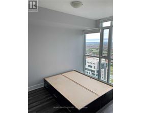 A bedroom with a large window overlooking a cityscape.