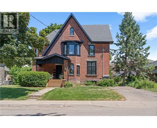 A brick house with a black roof and a green lawn in front.