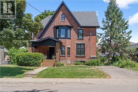 A brick house with a black roof and a green lawn in front.