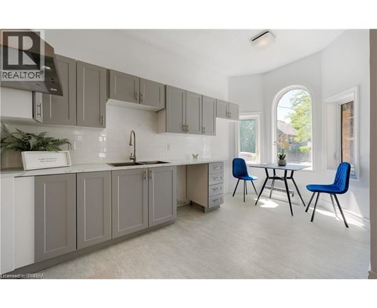 A kitchen with grey cabinets and a white countertop.