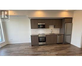 A kitchen with a refrigerator, oven, and microwave.