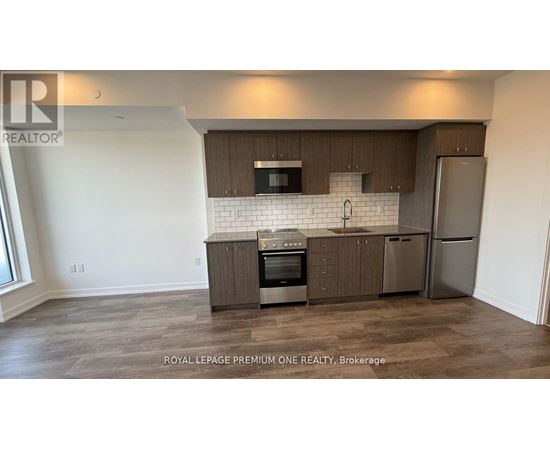 A kitchen with a refrigerator, oven, and microwave.