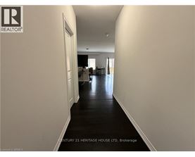 A long hallway with a door on the left and a kitchen area in the distance.