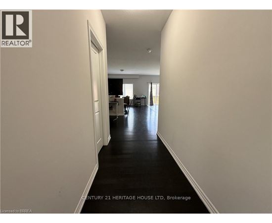 A long hallway with a door on the left and a kitchen area in the distance.