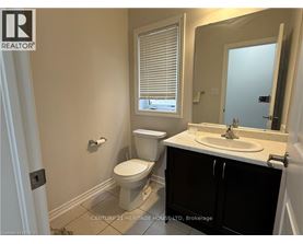 A bathroom with a toilet, sink, and window.