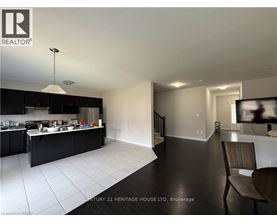 A modern kitchen with black cabinets and white tiled floors.