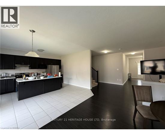 A modern kitchen with black cabinets and white tiled floors.