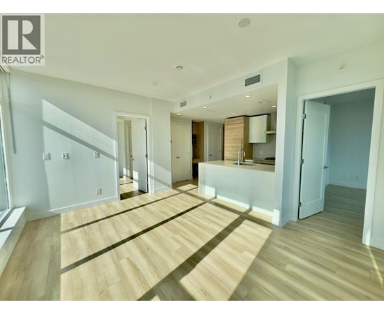 A spacious room with wooden flooring and white walls.