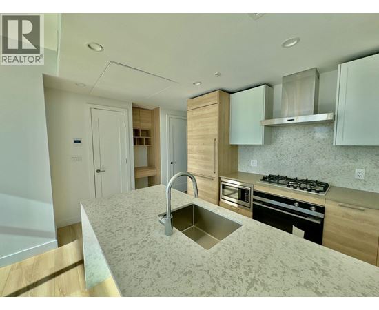 A modern kitchen with a sink, stove, and cabinets.
