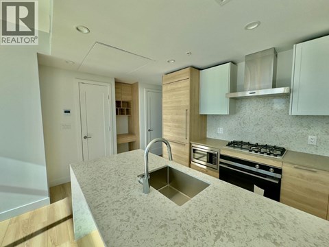 A modern kitchen with a sink, stove, and cabinets.