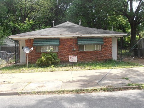 A red brick house with a sign on it.
