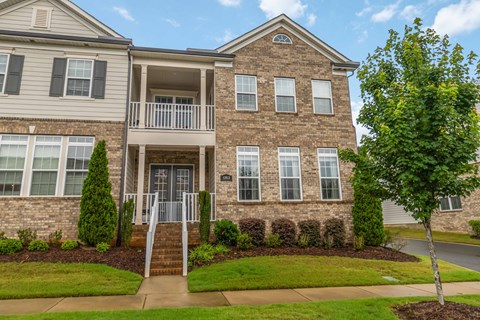 A two-story brick house with a balcony on the second floor.