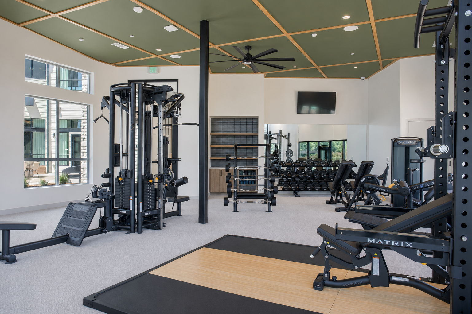 A gym with a variety of equipment including a treadmill, weights, and a bench.