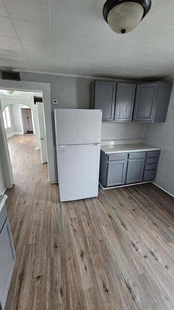 A kitchen with a white fridge and wooden floors.