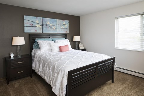 A bedroom with a large bed and two lamps.