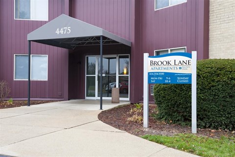 The front of a building with a sign that says Brook Lane Apartments.
