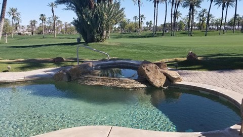 A pool with a rock in the middle and a fountain above it.