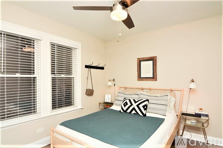 A bedroom with a bed, a ceiling fan, and a window with blinds.