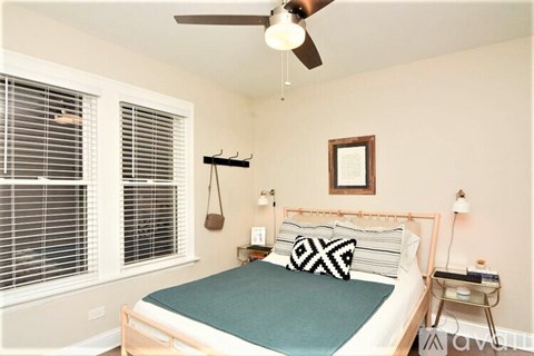 A bedroom with a bed, a ceiling fan, and a window with blinds.