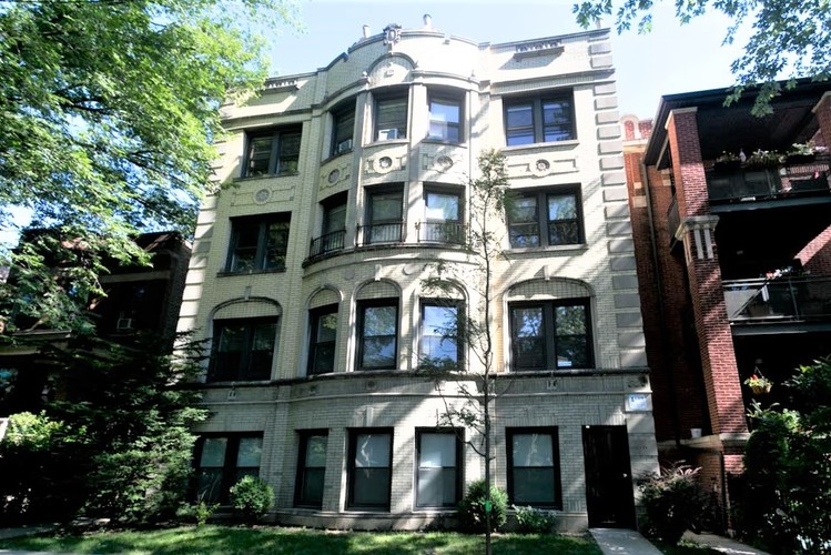 A large, old building with many windows is surrounded by trees.