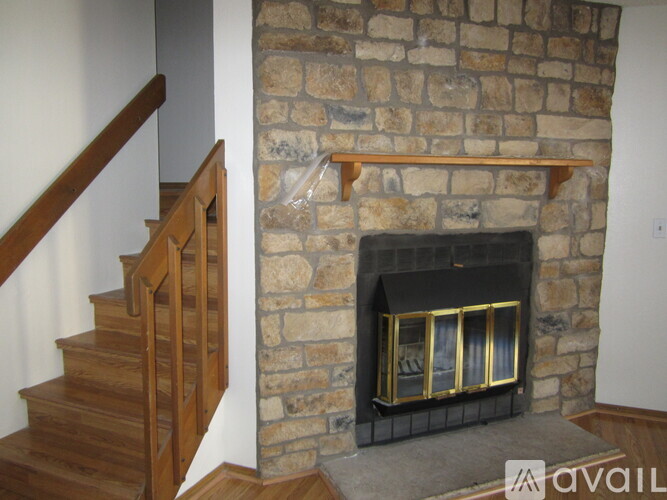 A stone fireplace with a wooden staircase on the left.